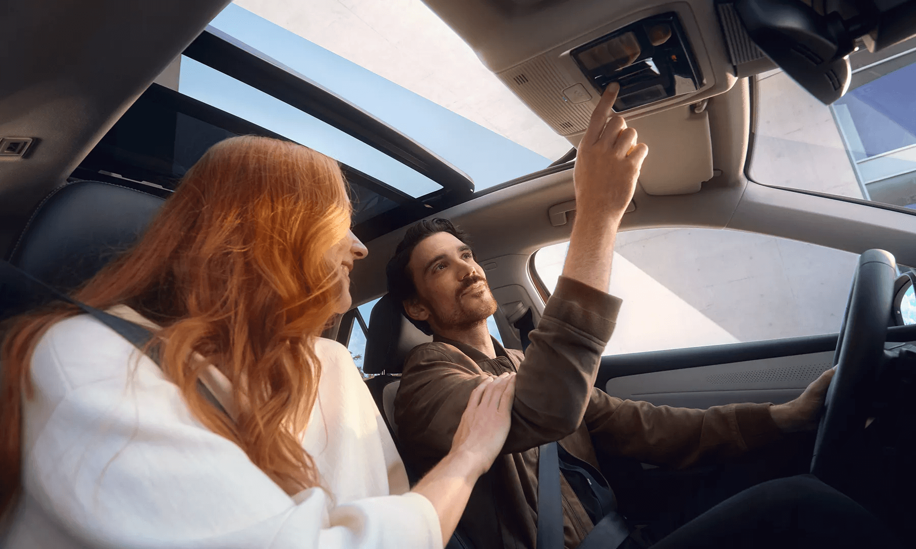 Pora automobilyje su atviru panoraminiu stogu ir saulėtu dangumi.