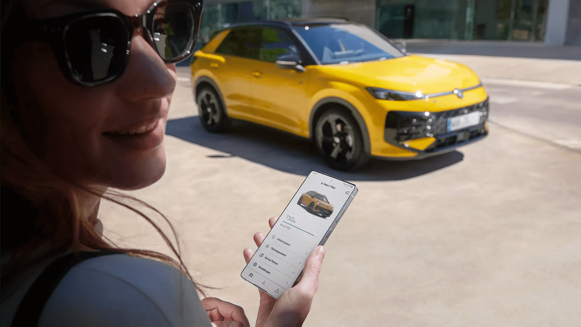 Moteris naudoja išmanųjį telefoną tikrindama prijungtą „Volkswagen T-Roc“.